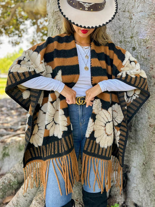 Camel and black striped fringe ruana layered over a white long sleeve tee and jeans