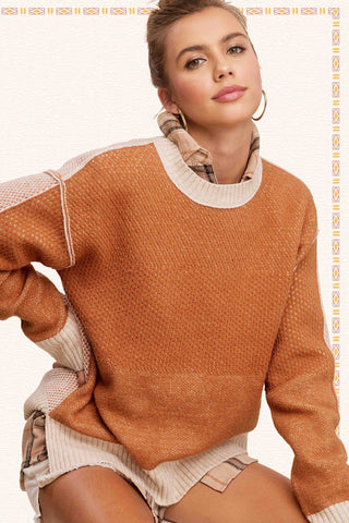 Front view of loose fit color block sweater with cream ribbed hem and side slits