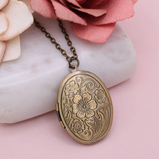Antique gold oval floral locket necklace with engraved flower design on burnished gold chain