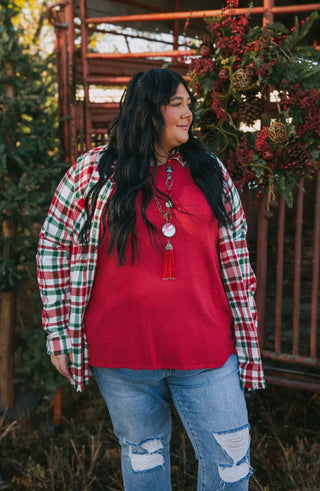 Red and green plaid flannel worn open over a red top with distressed jeans