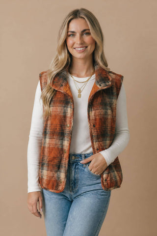Rust plaid puffer vest styled with a white tee and jeans