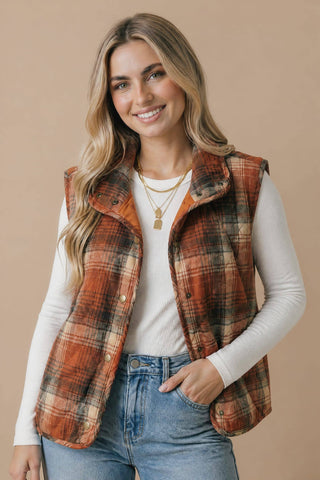 Rust plaid puffer vest worn open with jeans
