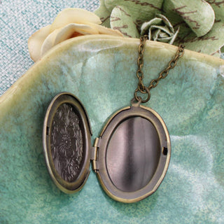 Gold floral locket necklace shown open with two photo compartments inside
