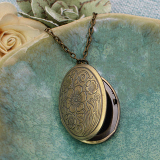 Close-up of vintage-inspired engraved floral locket pendant in gold tone metal