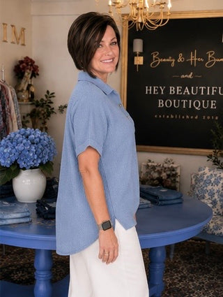 Woman in a blue shirt standing in a store with decorative elements and a sign.