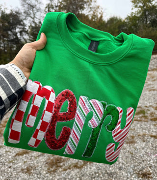 Close-up of sequin and stripe appliqué merry lettering on green sweatshirt