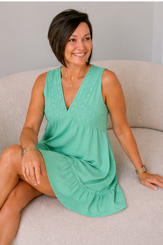 Woman wearing a green dress sitting on a beige couch.