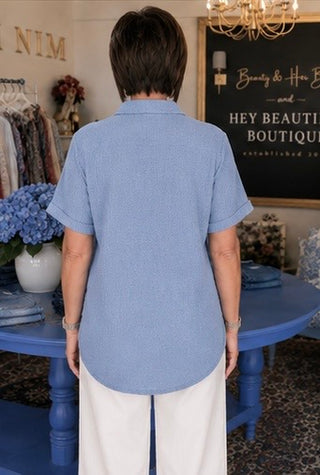 Person wearing a blue shirt in a store setting with a 'Hey Beautiful' boutique sign.