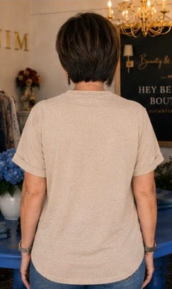 Person wearing a beige shirt in a room with a chandelier and decorative items.