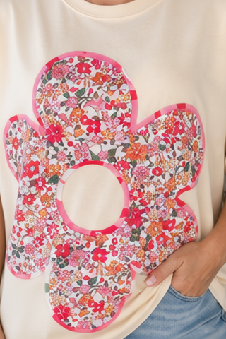 Floral-patterned bib held by a person wearing a white shirt and blue jeans.
