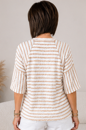 Person wearing a beige and white striped shirt with a neutral background