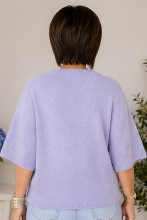 Person wearing a light purple sweater with a neutral background