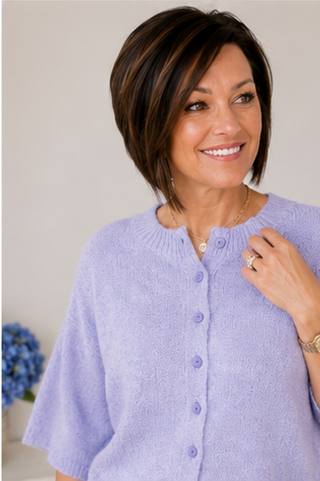 Woman wearing a light purple cardigan with a neutral background