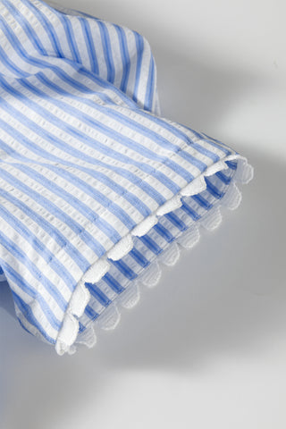 Blue and white striped fabric with ruffled edges on a gray background