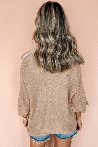 Close-up of soft beige knit sweater showing tonal contrast stripe texture and relaxed crew neckline