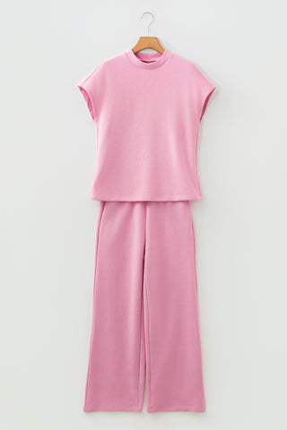 Pink outfit with top and pants on a hanger against a white background