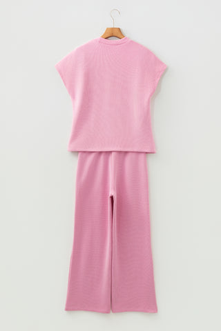 Pink sleeveless top and wide-leg pants set on a hanger against a white background