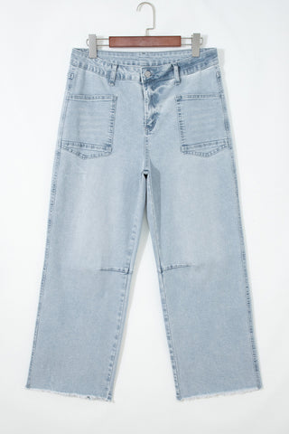 Light blue jeans hanging on a wooden hanger against a white background