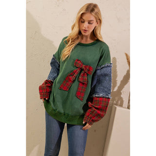 Green crewneck pullover with oversized red plaid bow, styled with jeans