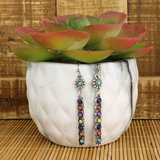 Silver bar dangle earrings with colorful multi stone accents shown on a white planter